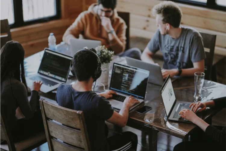 Five people sitting on a table with laptops