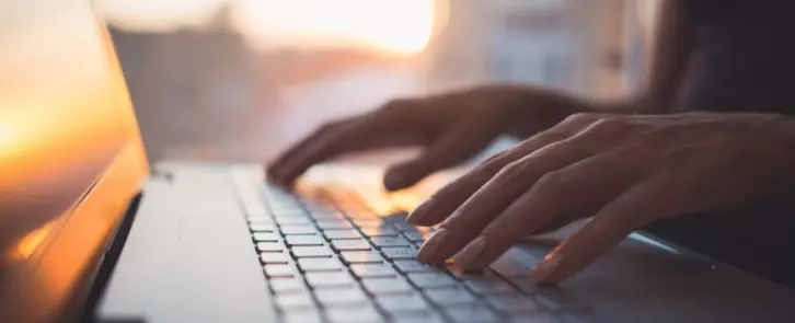 Hands typing on a laptop