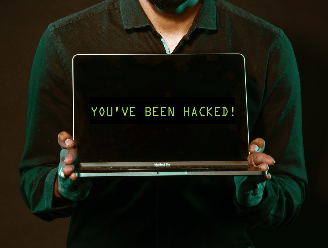 Person holding a computer that says "You've been hacked"
