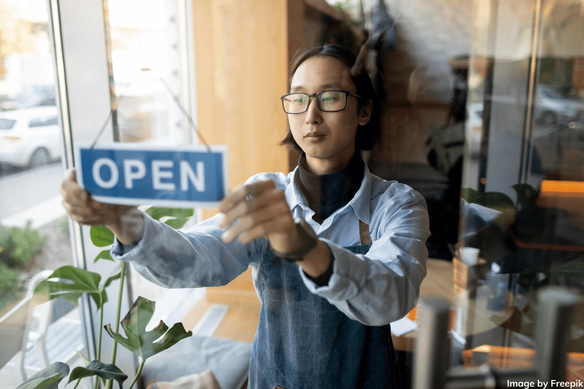 man turning small business sign to open