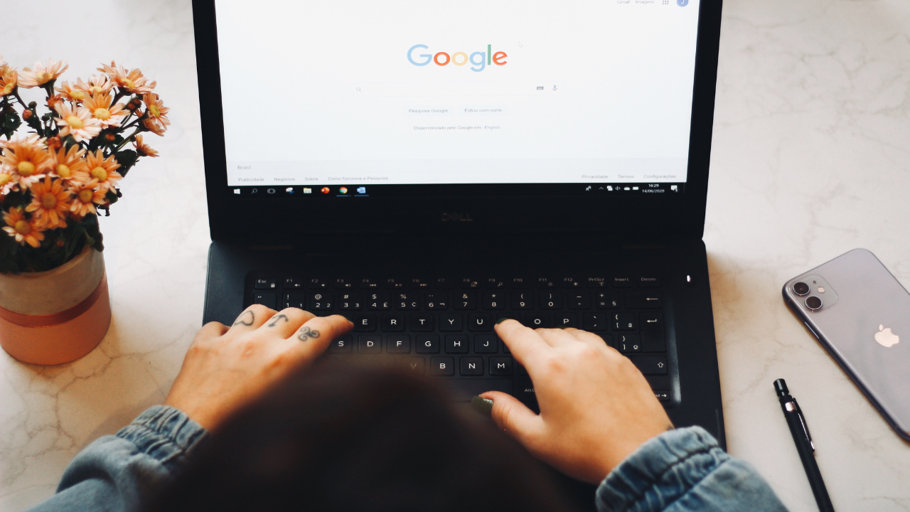 A person with tattoos logging in to Google on their laptop