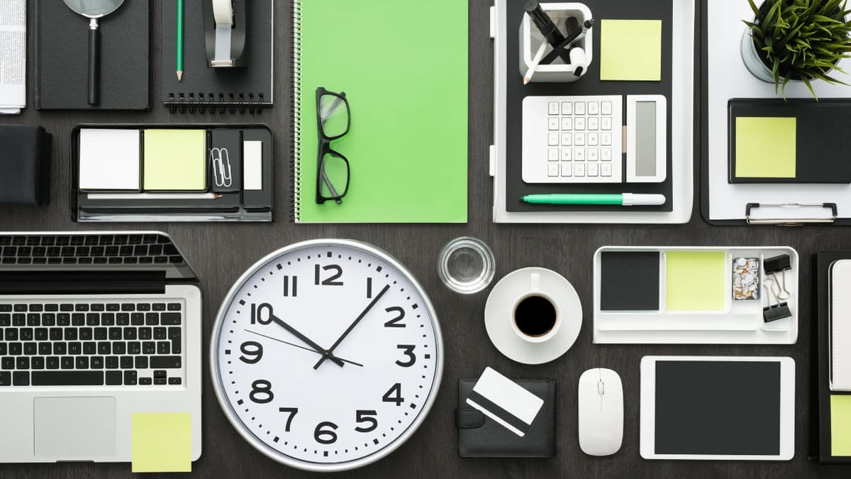 A black background with different office tools on it like a computer, mouse, clock, notebook, calculator, and more.