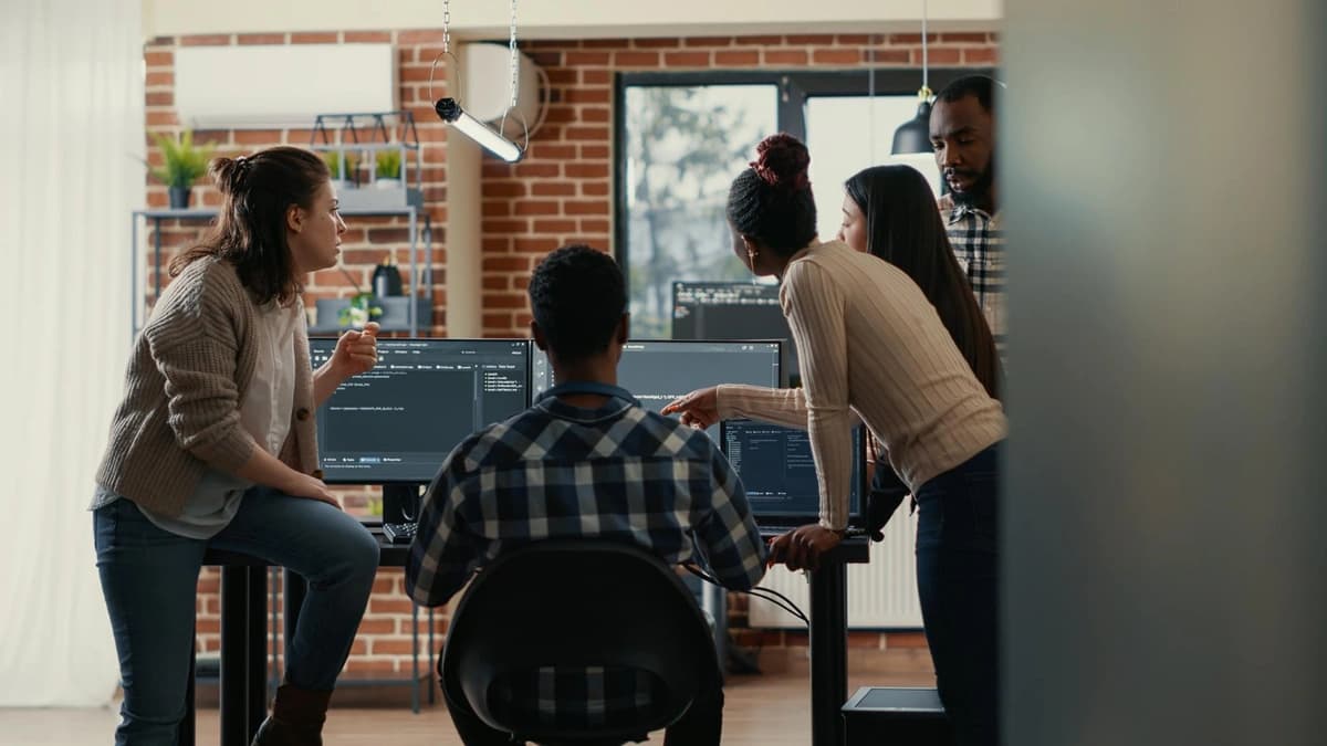 Employees standing around computer discussing code