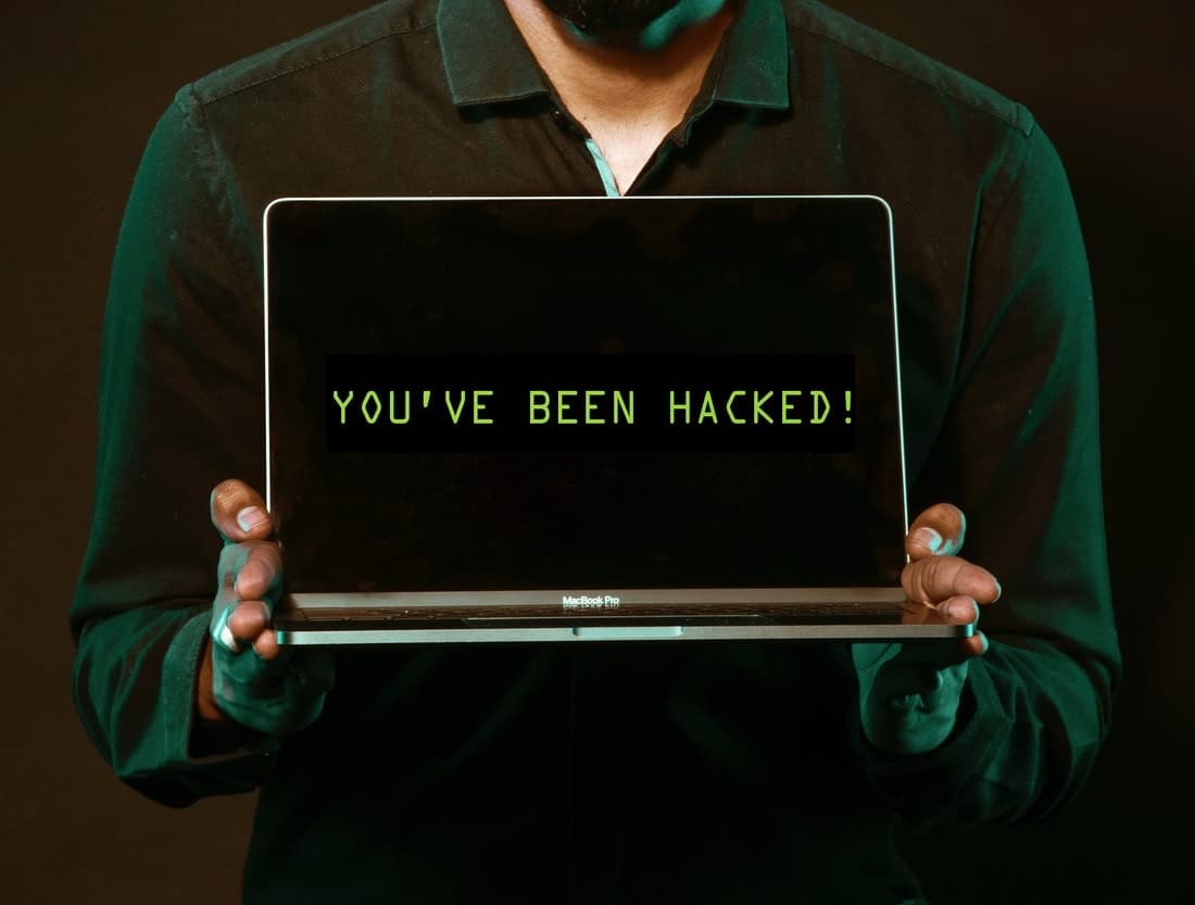 Person holding a computer that says "You've been hacked"