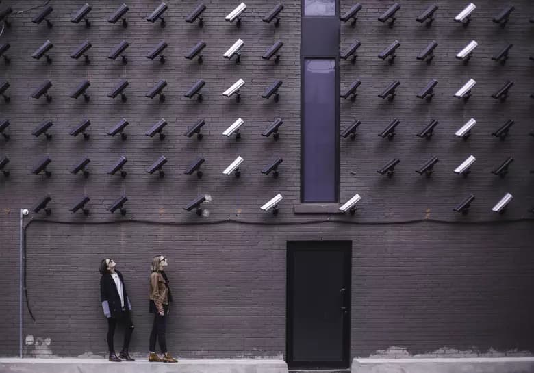 Two people looking up and many surveillance cameras pointing at them