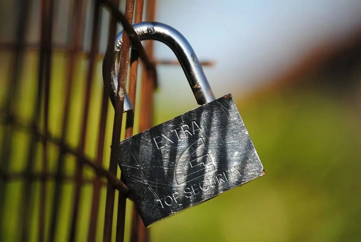 An open padlock attached to a fence